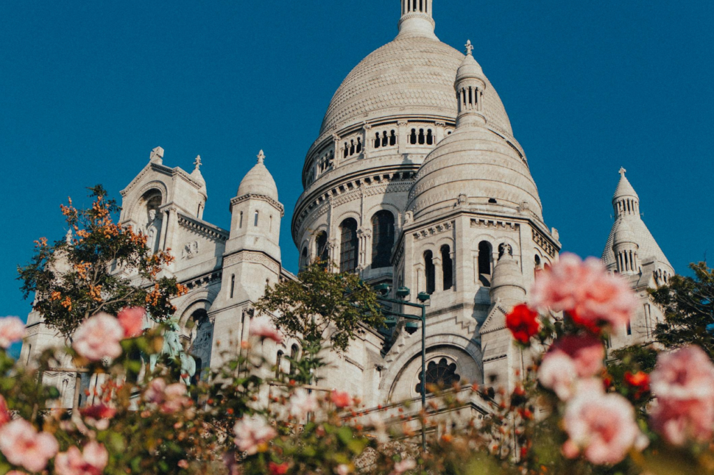 When Is the Best Time to Visit Paris? Sacré-Cœur Basilica in Montmartre surrounded by blooming flowers on a sunny day